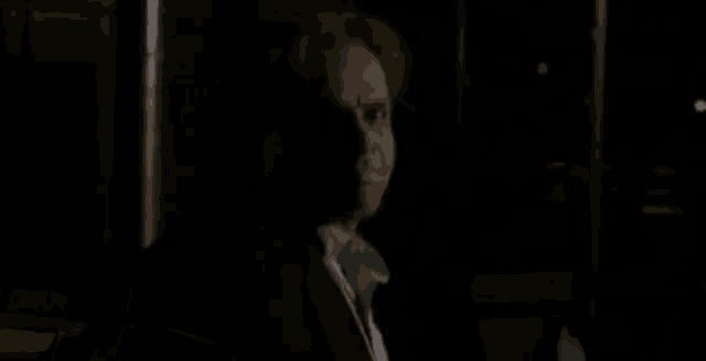 a person is standing in a dark room holding a knife .