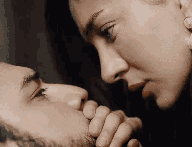 a close up of a woman kissing a man 's face