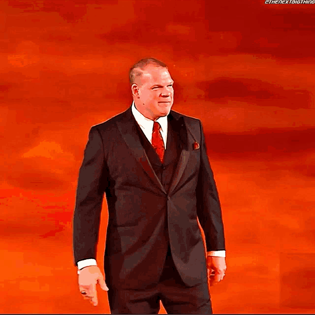a man in a suit and tie is standing in front of a sign that says kane