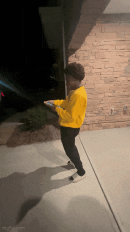 a young boy in a yellow hoodie is standing on a sidewalk