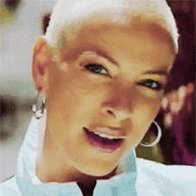 a close up of a woman 's face with a shaved head and hoop earrings