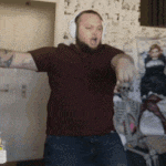 a man wearing headphones is standing in a room with his arms outstretched .