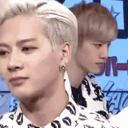 two young men are standing next to each other on a stage and one of them is wearing earrings .