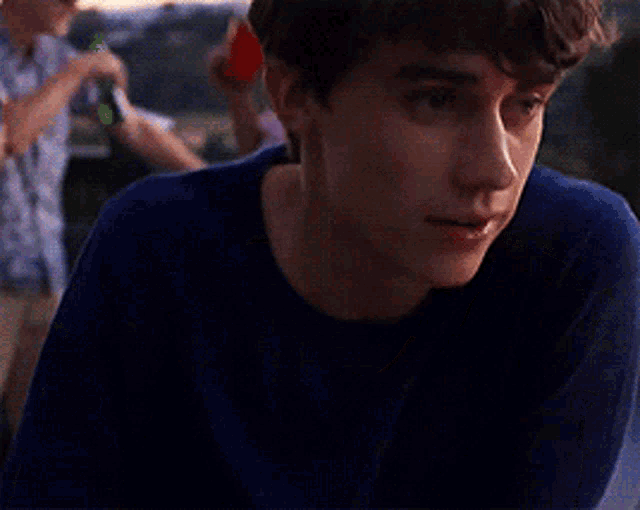 a young man in a blue shirt looks to his left