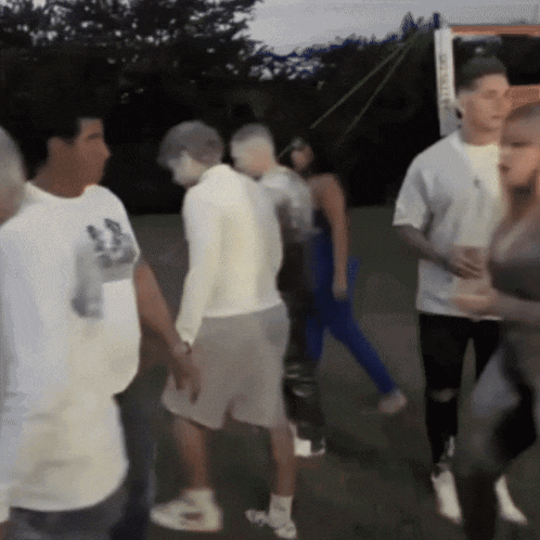 a group of people are walking in a park and one of them is wearing a shirt that says ' a ' on the front