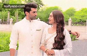 a man and a woman are holding hands and looking at each other while standing next to each other .