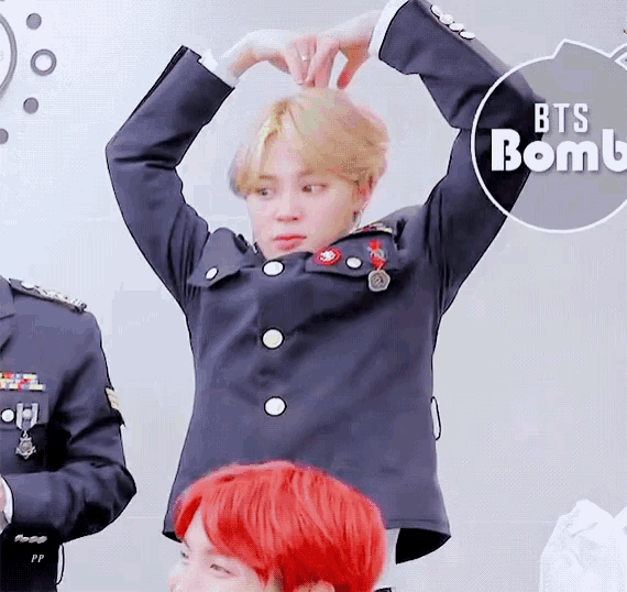 a man in a military uniform is making a heart shape with his hands in front of a sign that says bts bomb