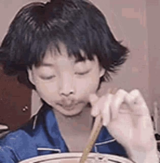 a young girl is eating soup with chopsticks .