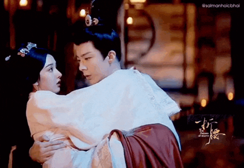 a man is carrying a woman in his arms in a traditional costume .