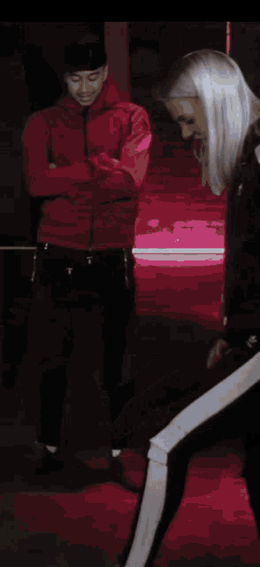 a man in a red jacket stands next to a woman in a black jacket