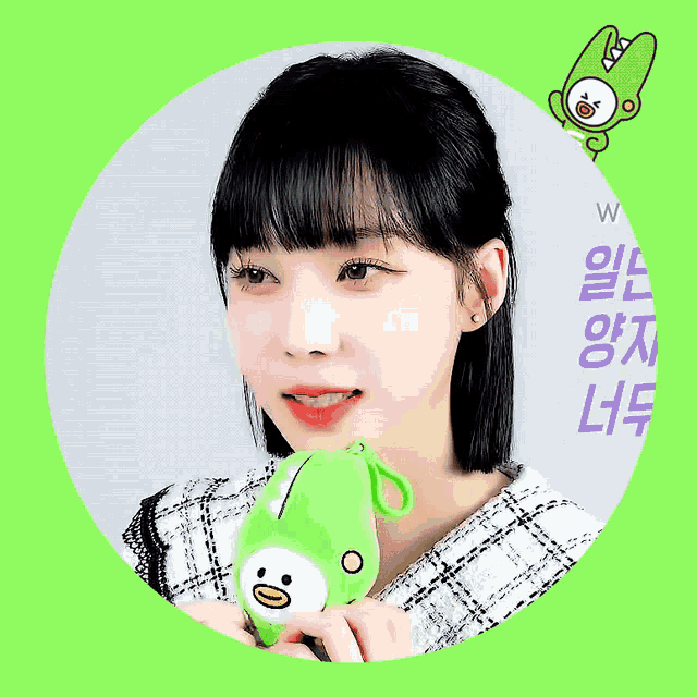 a woman is holding a green stuffed animal in front of a green background with chinese characters