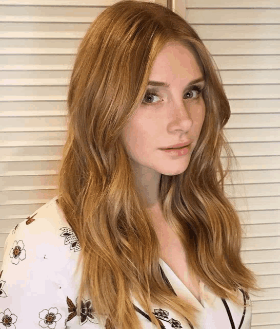 a woman with long blonde hair is wearing a floral shirt