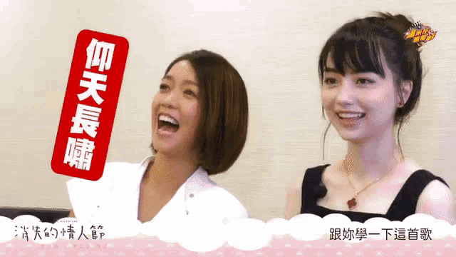two women are laughing and one has a sticker that says ' i love you ' on it