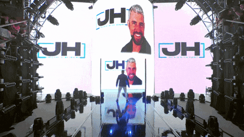 a man stands in front of a screen that says jh on it