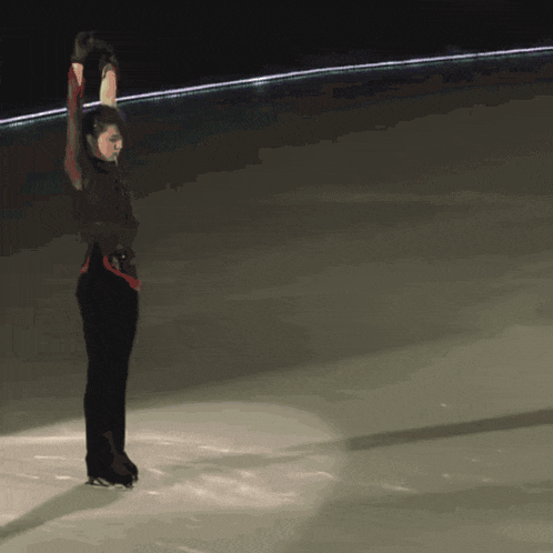 a man is standing on a ice rink with his arms up