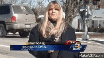 a woman is holding a microphone in front of a sign that says the top 5 train derailment norwood