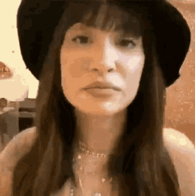 a close up of a woman wearing a hat and a necklace .