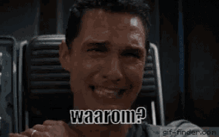 a man is sitting in a chair with his hand to his mouth and the words waarom written on the screen behind him .