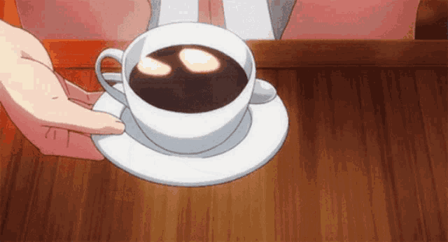 a person is holding a cup of coffee on a saucer on a table