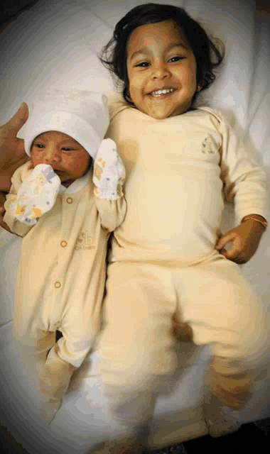 a baby and a toddler are laying on a bed