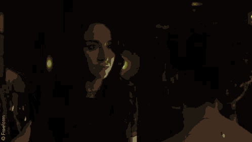 a woman with green hair is looking at herself in a mirror in a dark room .