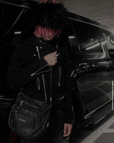 a man with red hair is standing in front of a car