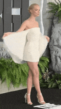 a woman in a white dress is standing in front of a sign that says " sky "
