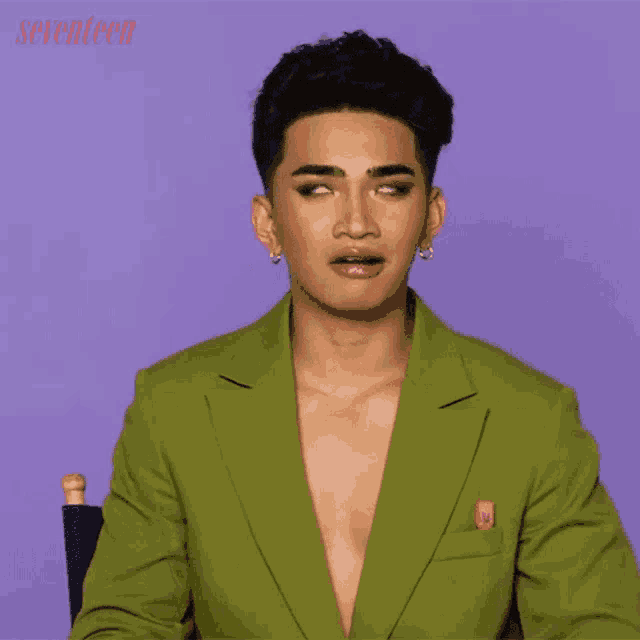 a man in a green suit is sitting in front of a seventeen poster