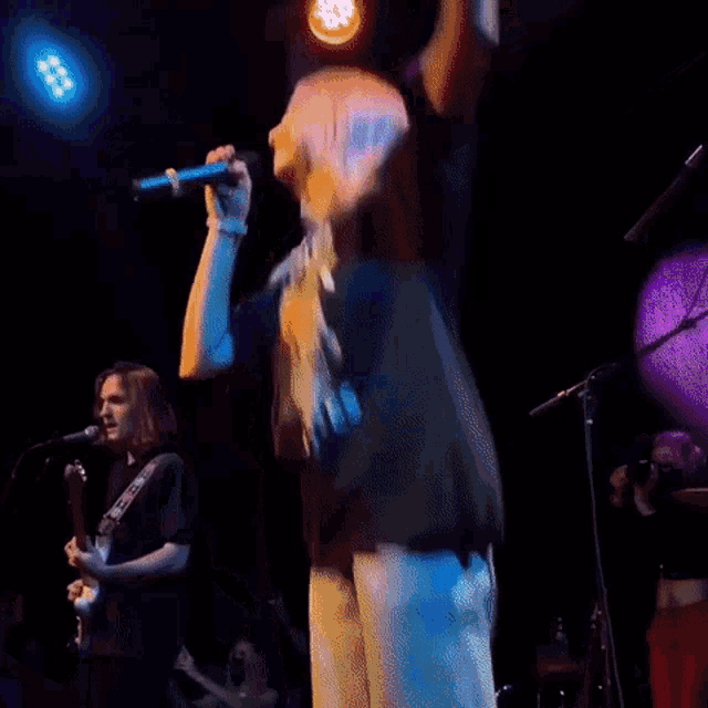a woman singing into a microphone with a shirt that says hooks on it