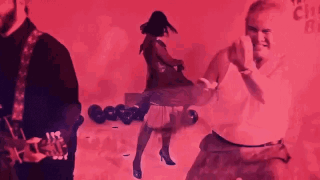 a man playing a guitar and a woman dancing in a red background