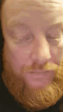 a man with red hair has his eyes closed