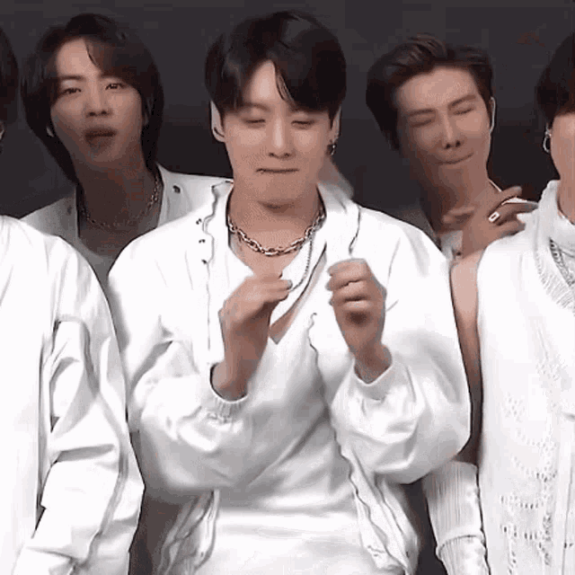 a group of men standing next to each other wearing white shirts and jackets .