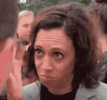 a woman in a suit is making a funny face while standing in a crowd .
