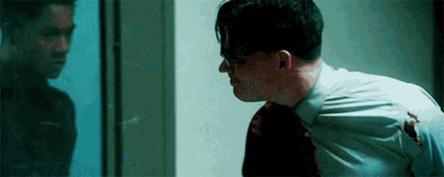 a man wearing glasses and a white shirt is standing in front of a glass door .