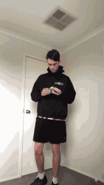 a man wearing a black hoodie with the word swag on it holds a yellow rubik 's cube