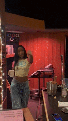 a woman in a crop top is dancing in a room with a red wall