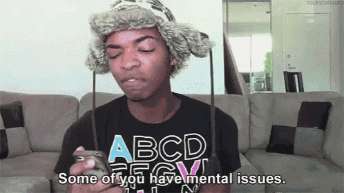 a man wearing a hat and a t-shirt that says " some of you have mental issues " looks at his phone