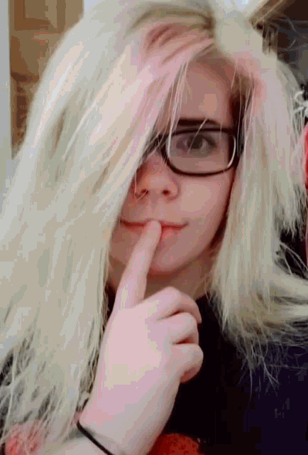 a girl with long blonde hair and glasses is covering her face with her hand