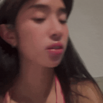 a close up of a woman 's face with her eyes closed . she is wearing a pink bikini top .