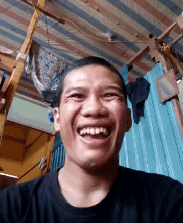 a man in a black shirt is laughing with his mouth open