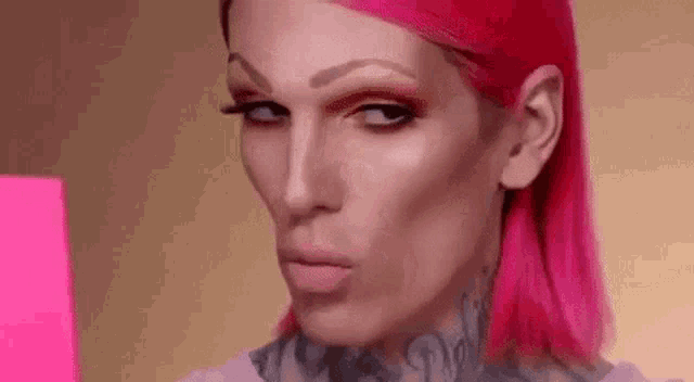 a close up of a person with pink hair looking at a pink box .