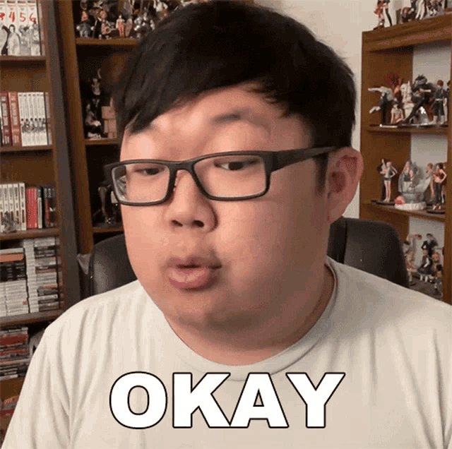 a man wearing glasses and a white shirt with the word okay on it