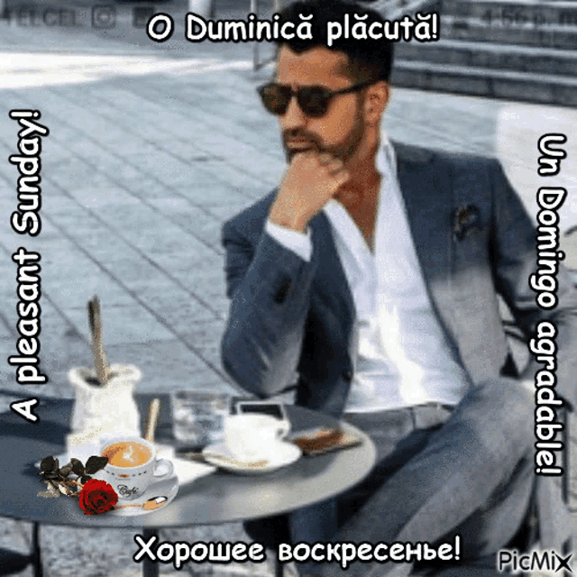 a man in a suit is sitting at a table with a cup of coffee and a rose