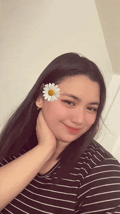 a woman wearing a black and white striped shirt has a white flower in her hair .