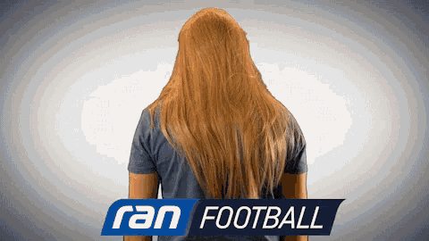 a person with long hair stands in front of a ran football sign