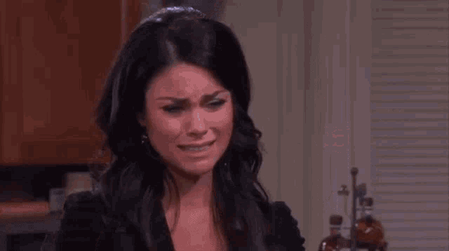 a woman is crying while sitting in a kitchen .