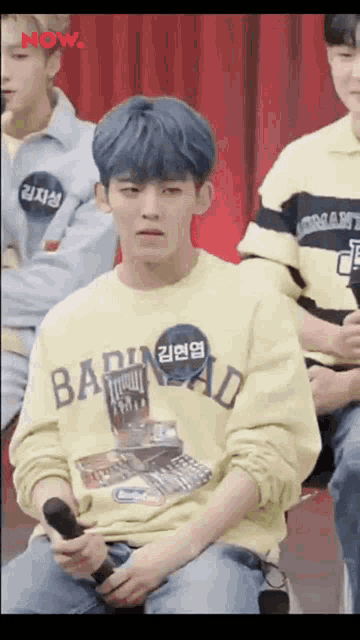 a boy with blue hair is wearing a yellow sweater that says bad head