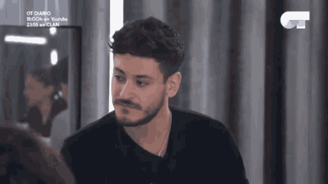 a man with a beard is standing in front of a mirror and looking at a woman .
