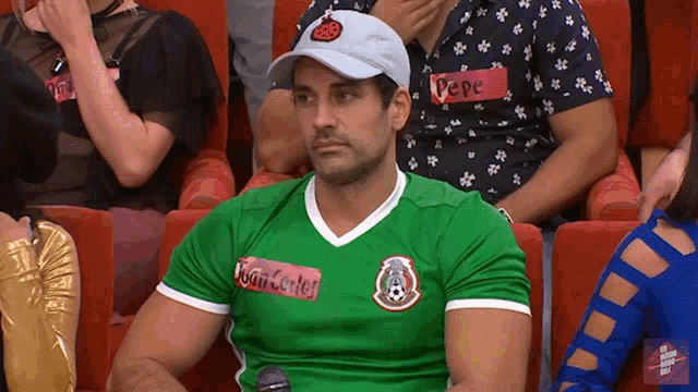 a man with a name tag that says pepe sits in a crowd