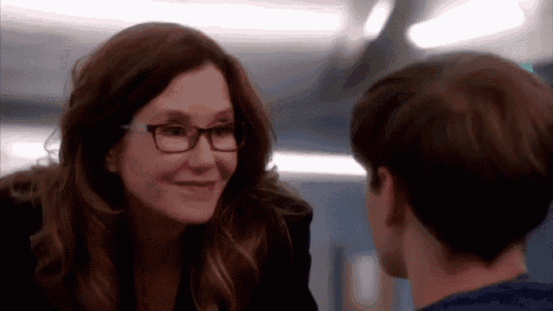 a woman wearing glasses is talking to a young man in a room .